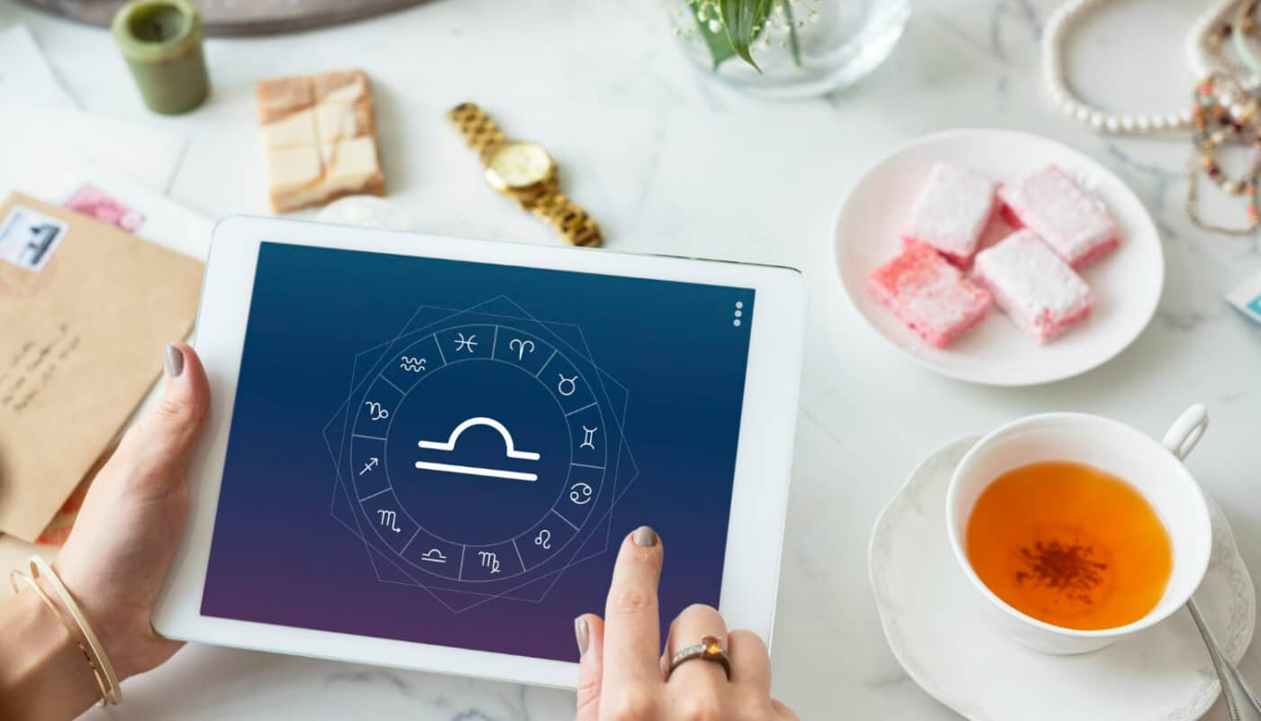 Mains tenant une tablette affichant les signes astrologiques