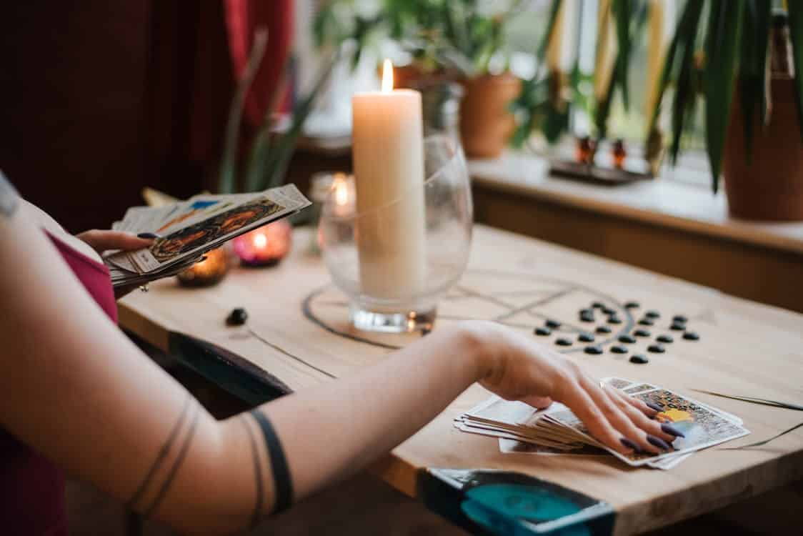 plan sur des mains de femme posés sur des cartes de tarot